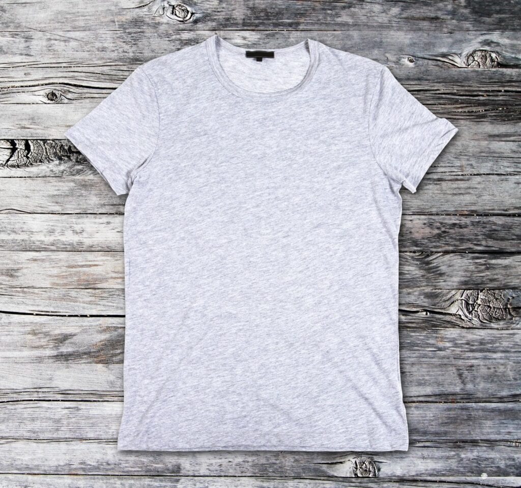 A white t-shirt is on the wooden floor.