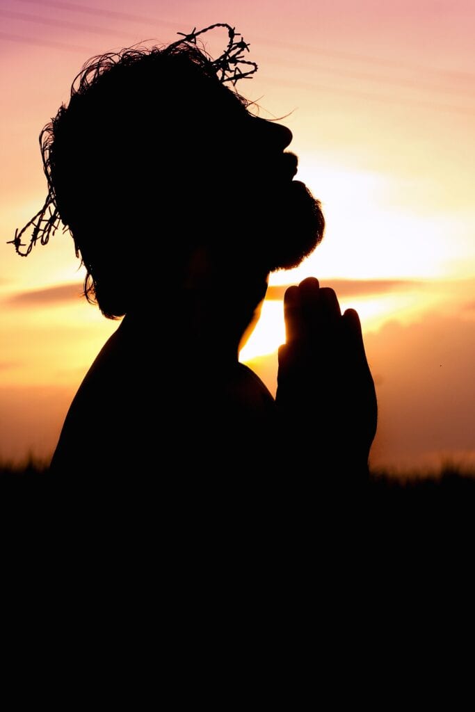 A person is praying in the sunset.