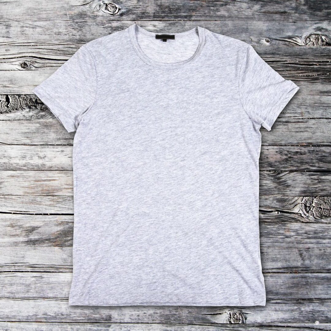 A white t-shirt is on the wooden floor.